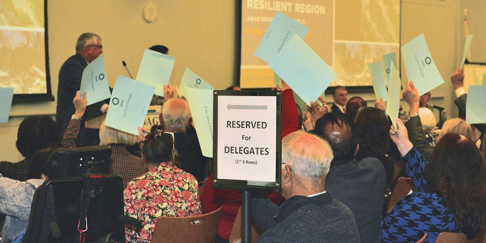 Voting members holding up signs during a General Assembly meeting.